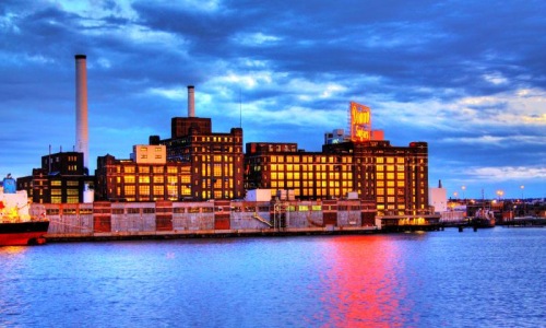 a large building with smokestacks by a body of water