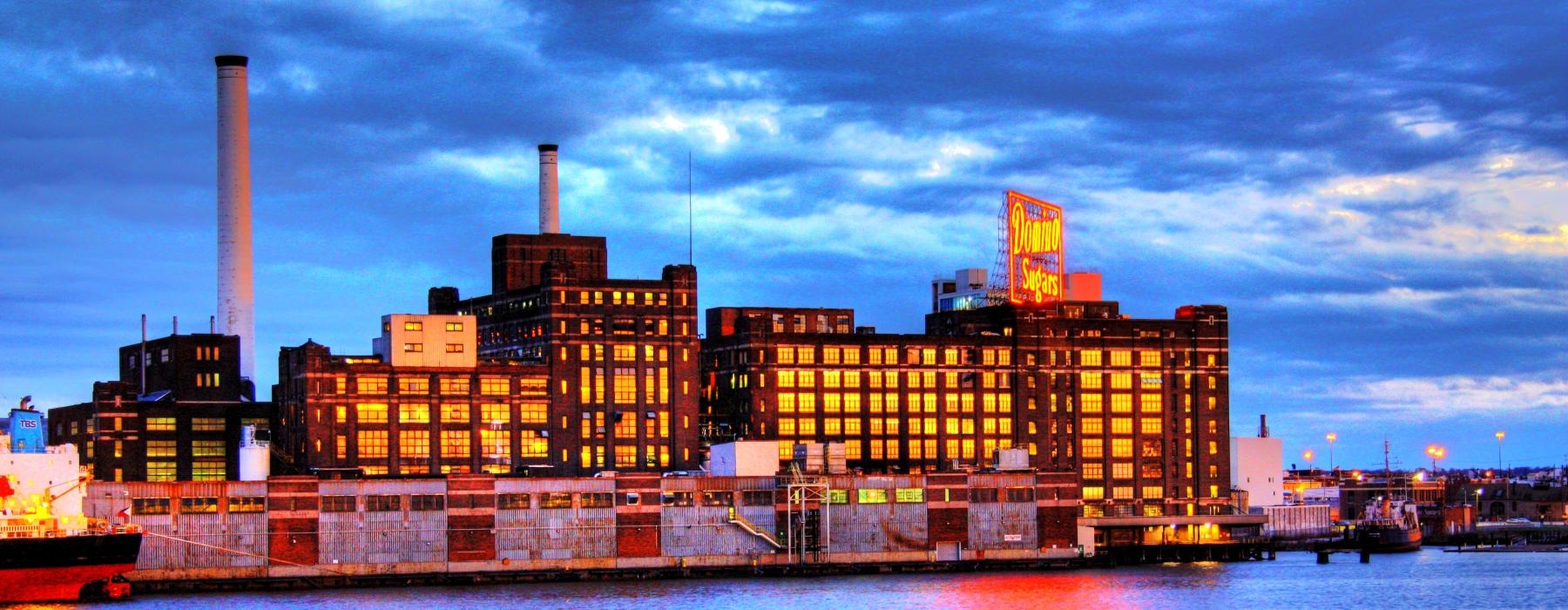 a large building with smokestacks by a body of water